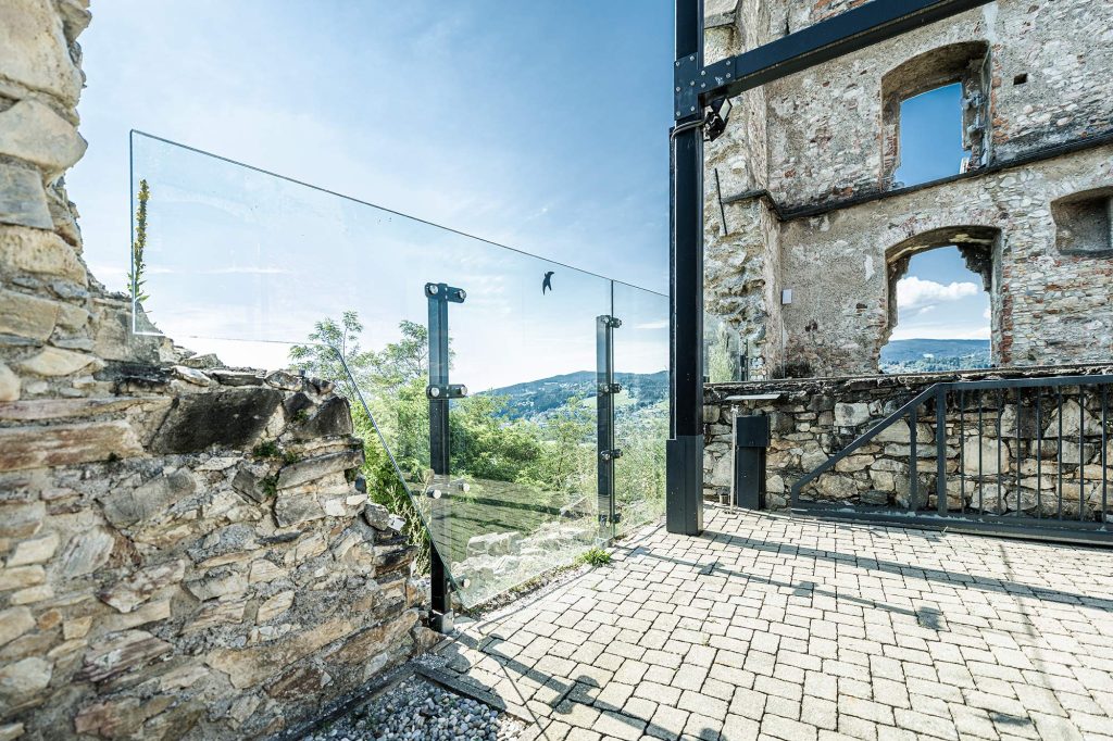 Mauerreste der Burgruine Obervoitsberg mit einer Dachkonstruktion aus Stahl sowie einer Absturzsicherung als Stahl und Glas.